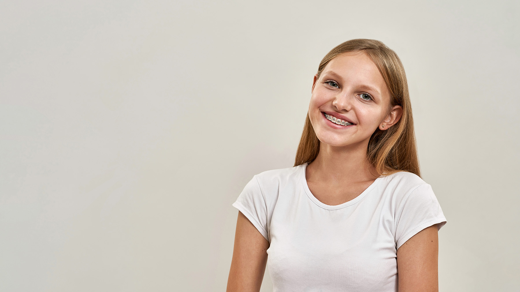 A young girl with light hair smiles at the camera.