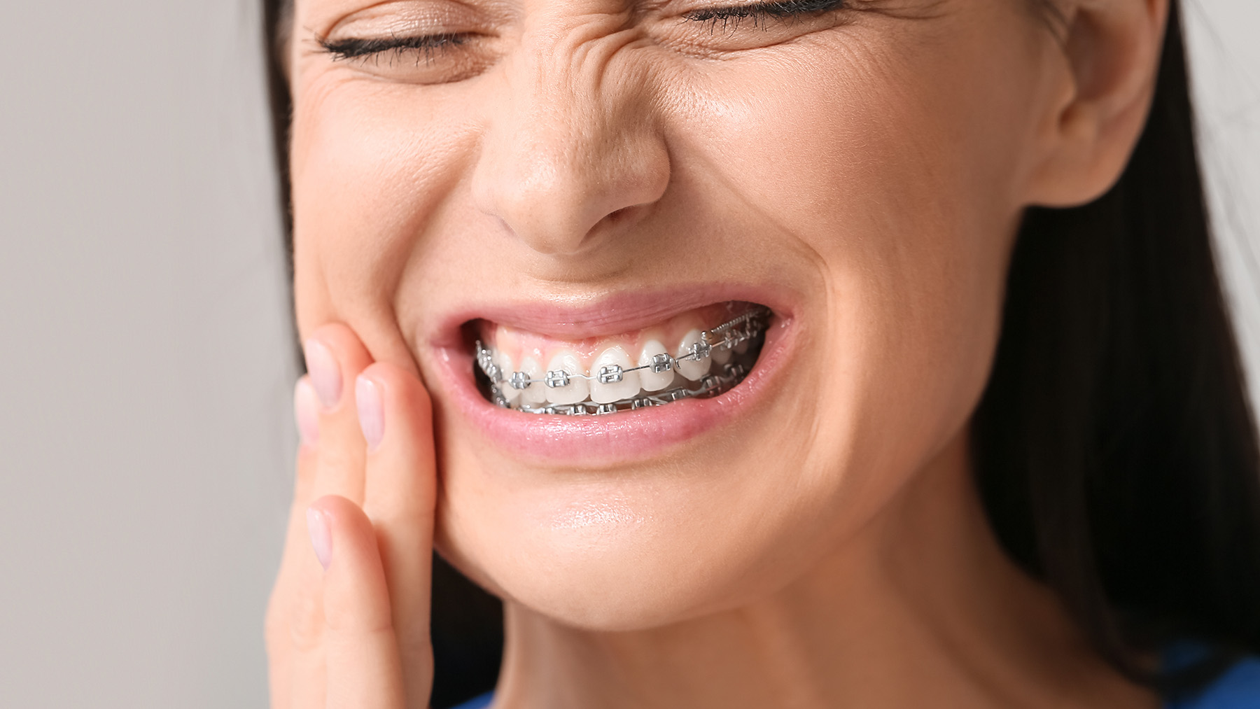 The image shows a smiling woman with braces, looking directly at the camera.