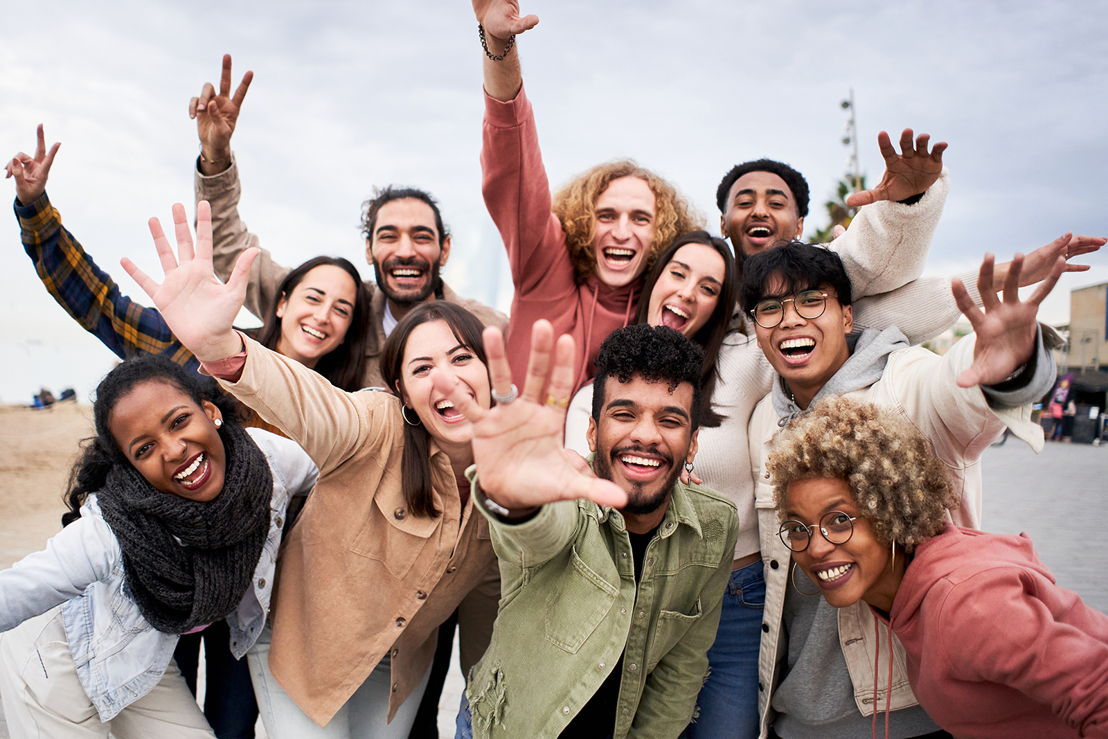 The image shows a group of people celebrating with raised arms, likely posing for a photo at an outdoor event.