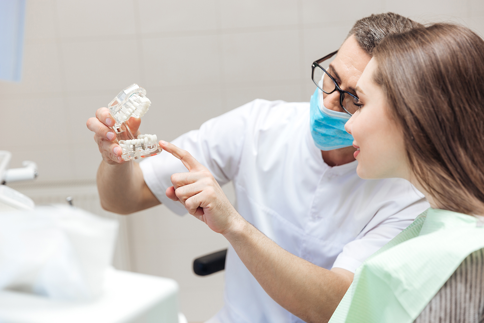 A dentist examining a patient s teeth while holding up a toothbrush.