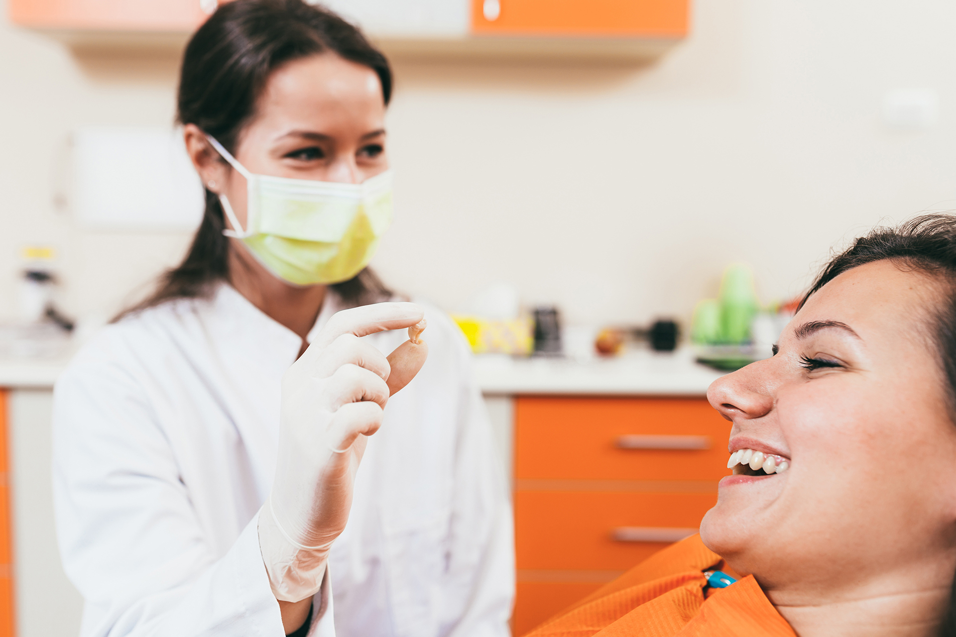 A dental hygienist assisting a patient with an oral examination in a dental office setting.