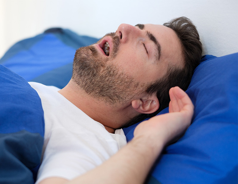 Man sleeping on bed with beard and closed eyes.