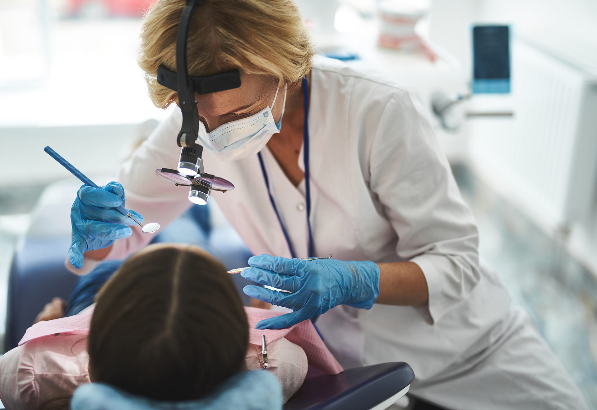 A dental hygienist performing a dental procedure on a patient's mouth.