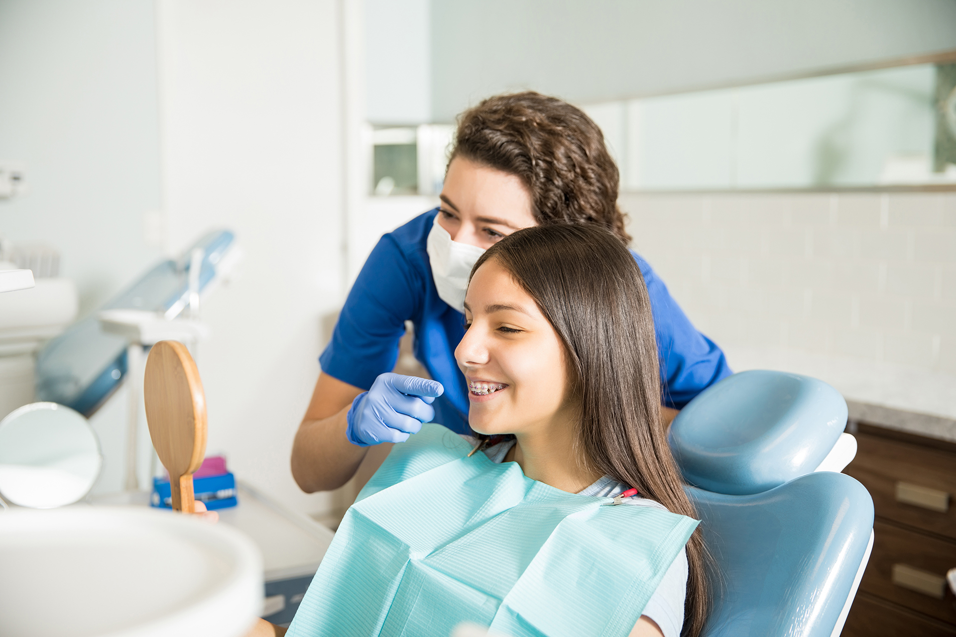 A dental hygienist assisting a patient during a teeth cleaning appointment at a dental office.