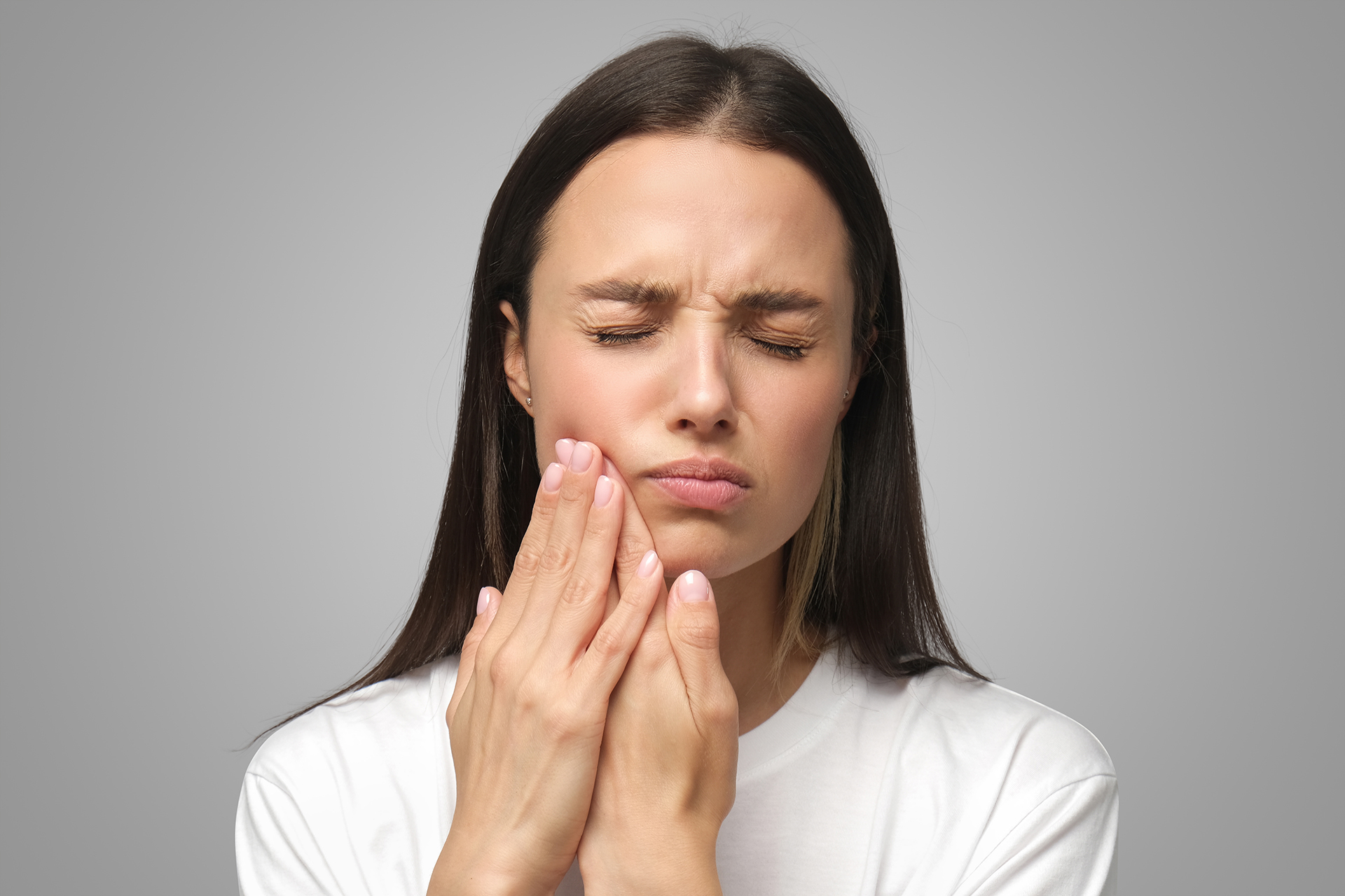 The image displays a woman with her eyes closed and hand on her chin, seemingly experiencing discomfort or pain, possibly related to dental care or oral health, given the context of her expression and hand placement.
